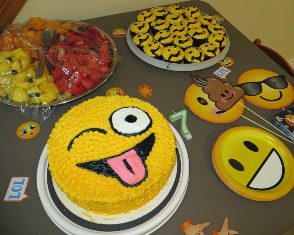 Emoji theme cake, cupcakes, and decorations.