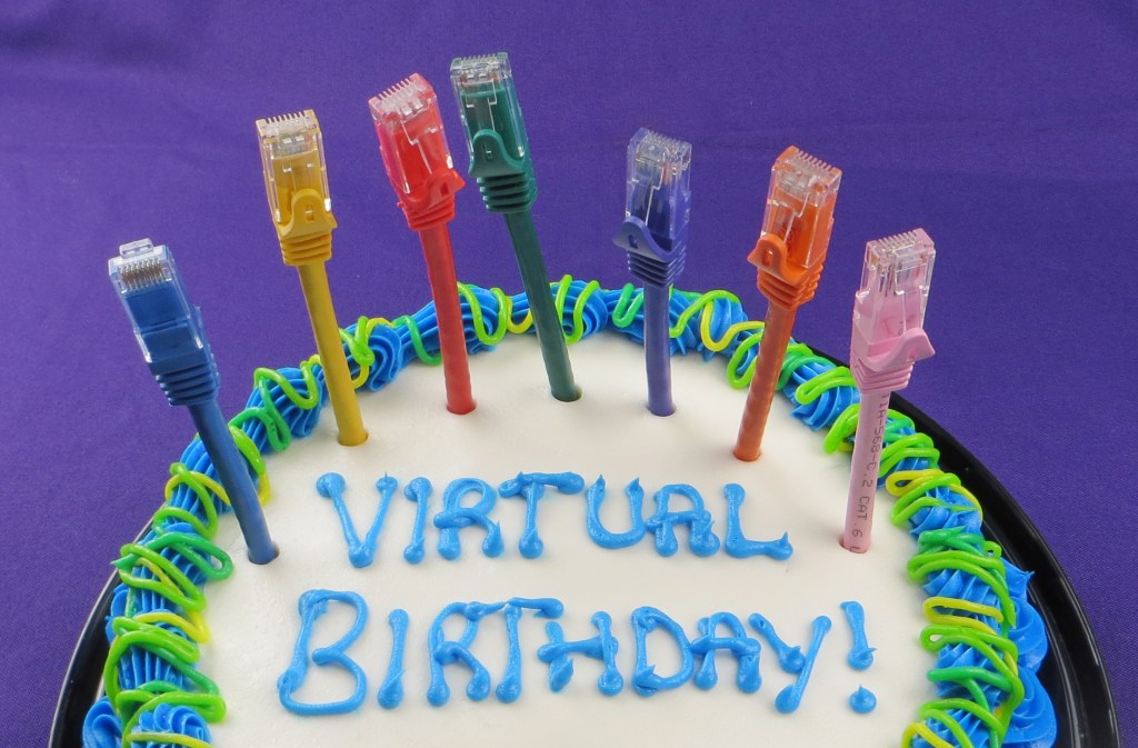 Birthday cake with colorful internet modem plugs instead of candles. Icing writing reads Virtual Birthday.
