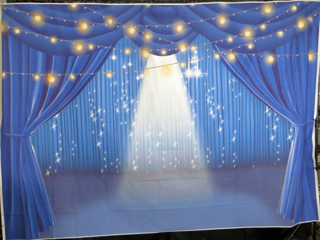 Photography backdrop representing parted blue theatrical curtains with many shiny lights all over it.