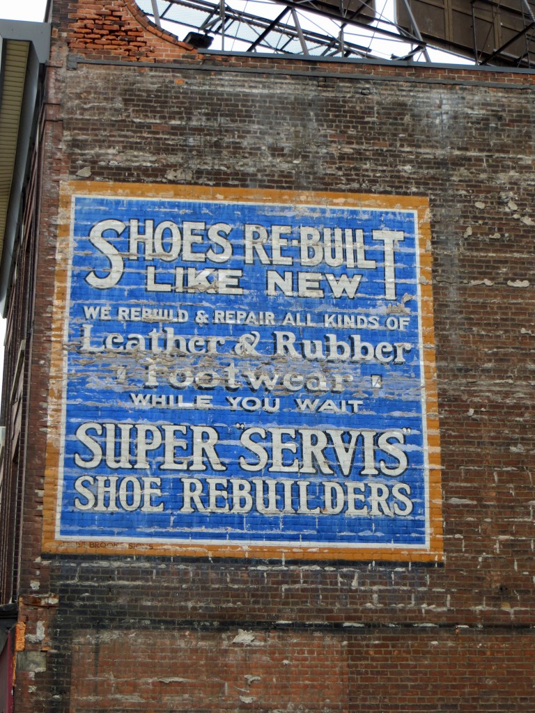 Old well preserved exterior wall advertisement for a shoe repair store.
