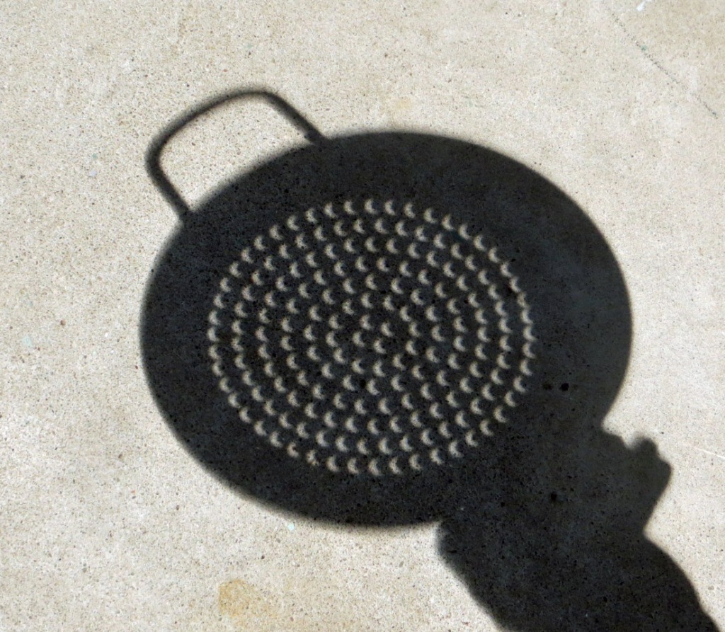 Shadow of vegetable steamer with about 200 tiny partial eclipses visible. One in every hole of the steamer.