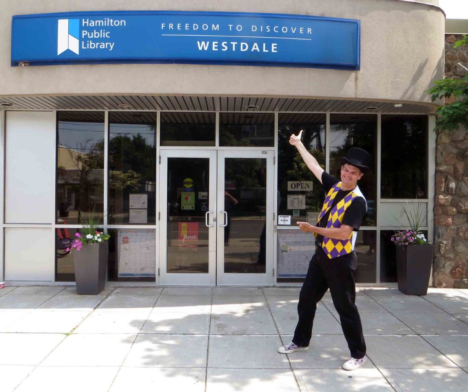 Magician Owen standing in front of Westdale Branch library after a show there.