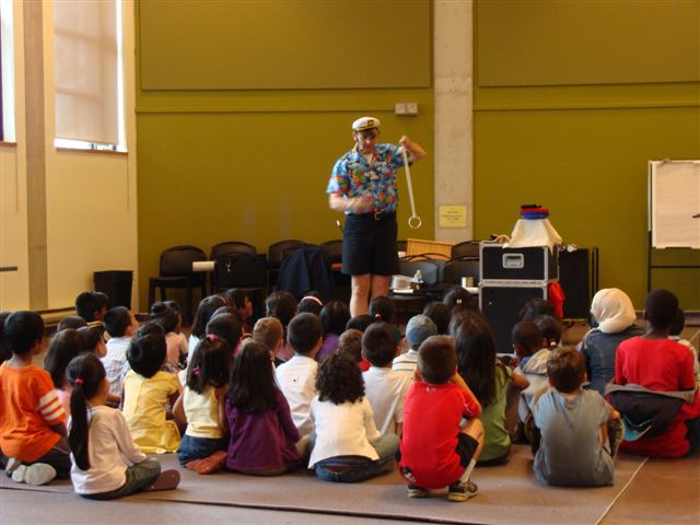 Magician Owen performing for a group of kids at a summer show.
