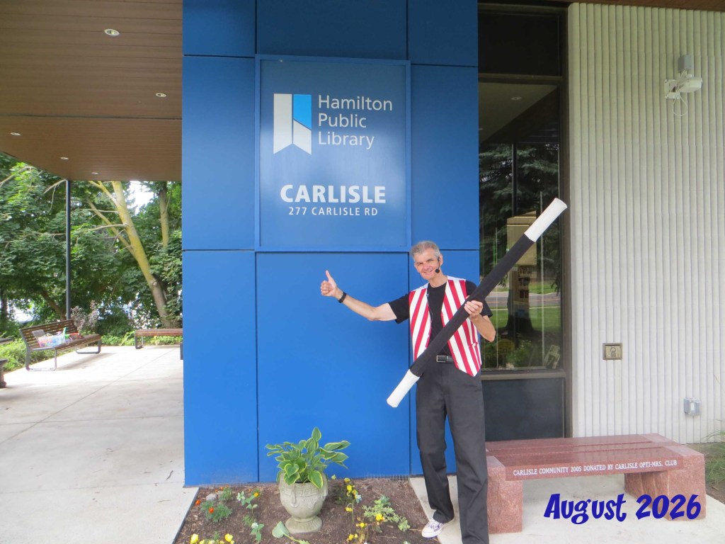 Owen in costume standing in front of branch signage for Carlisle library.